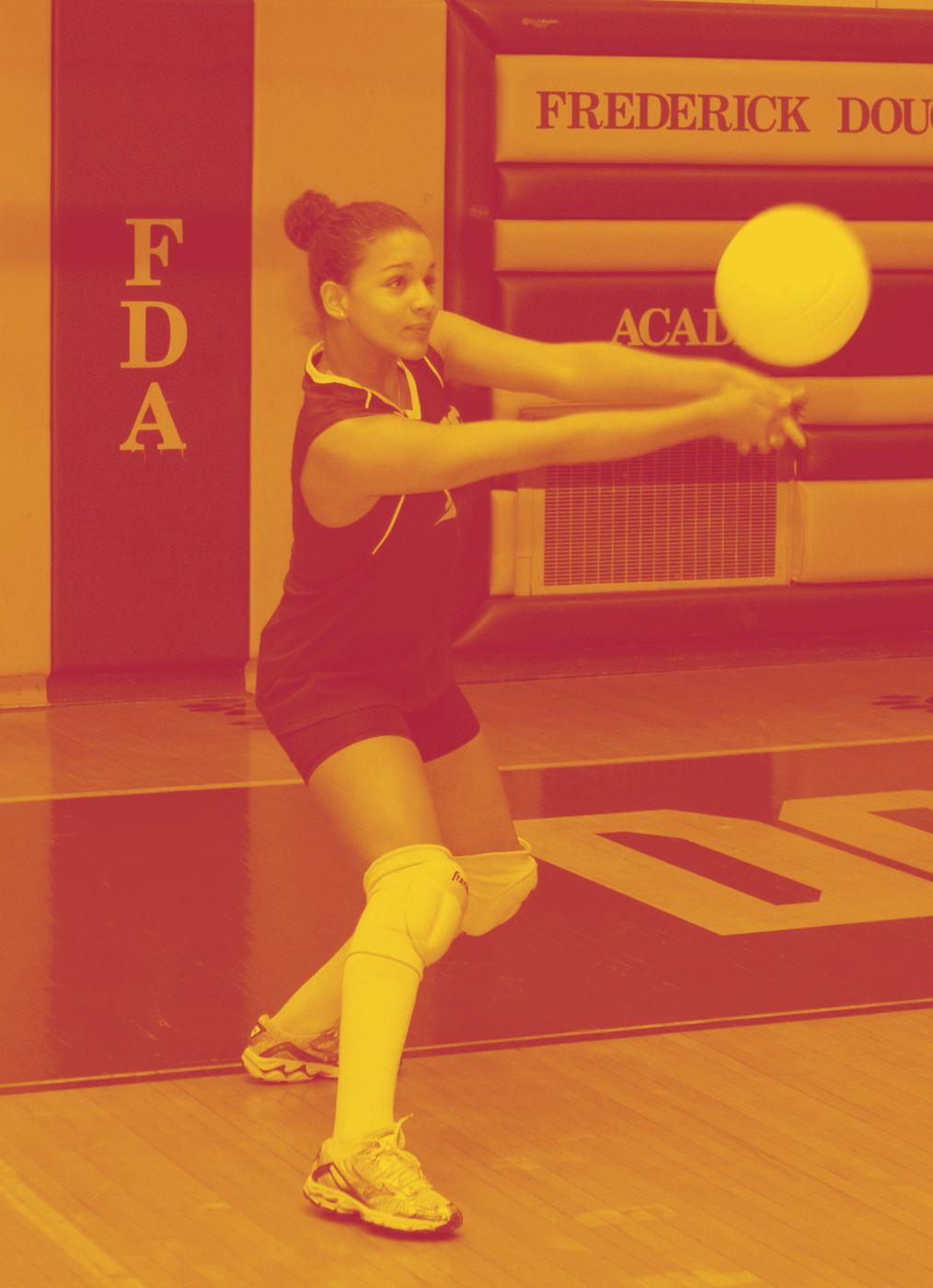 An FDA volleyball player serving in the school gym.
